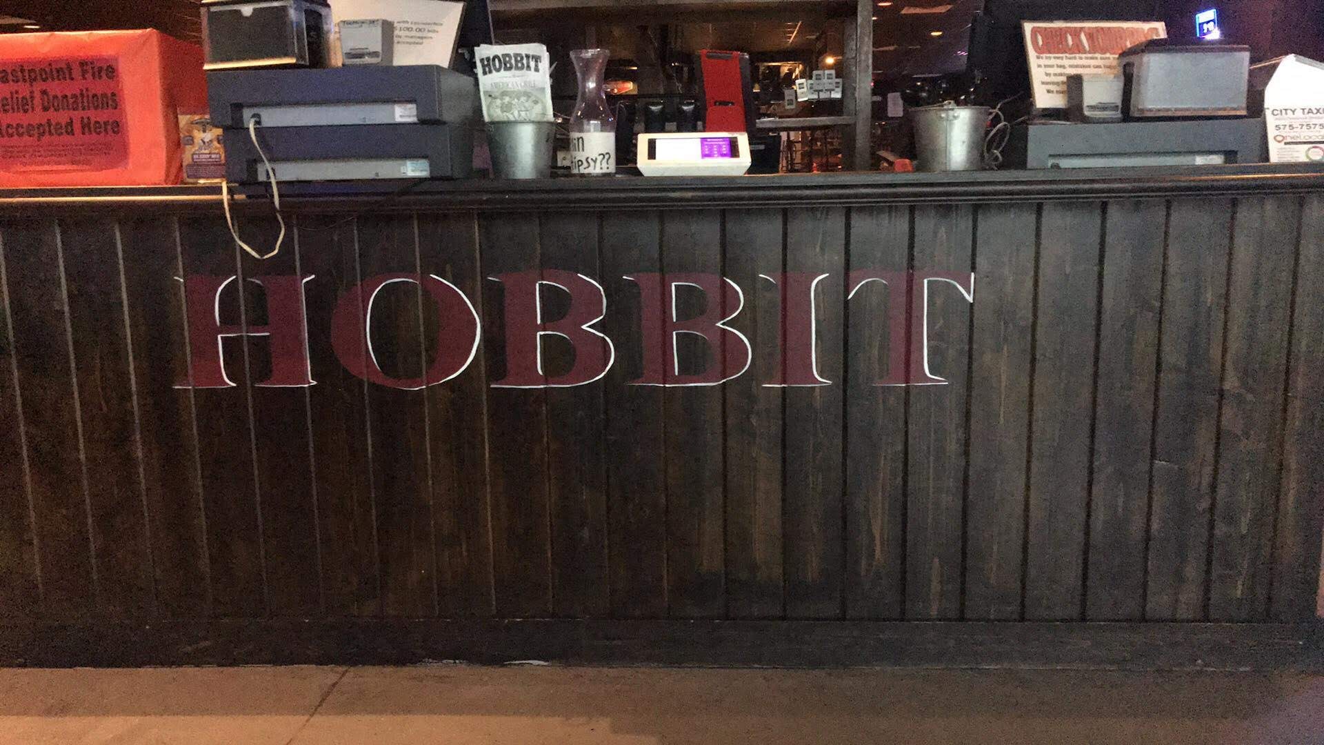 The word Hobbit carved into the dark wood panelling behind the bar.