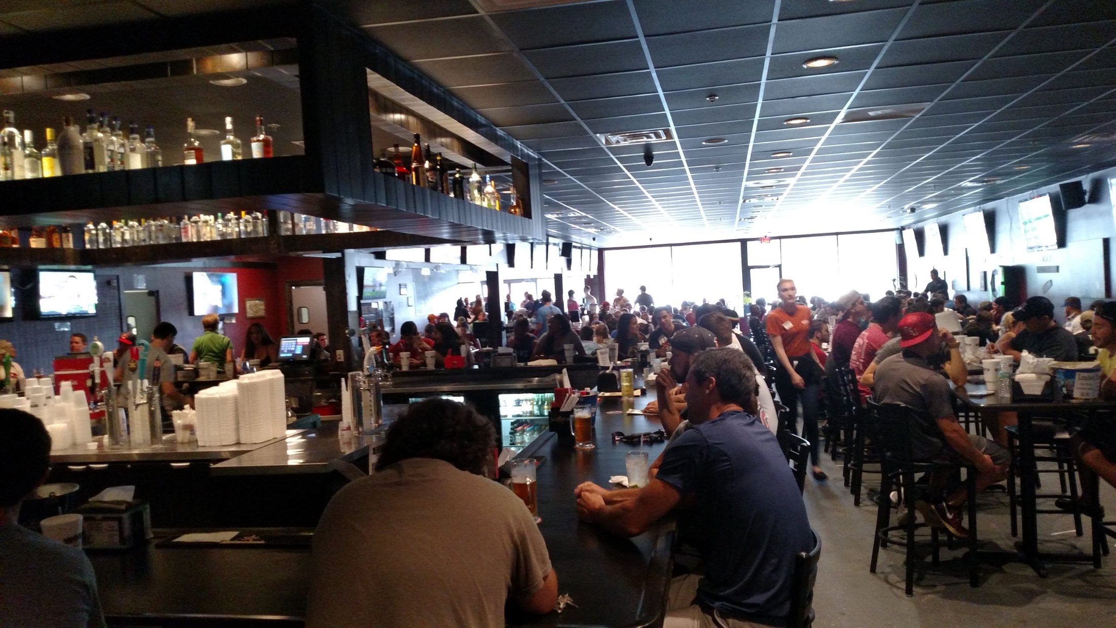 The dining room full of people at long tables, with televisions along the wall.