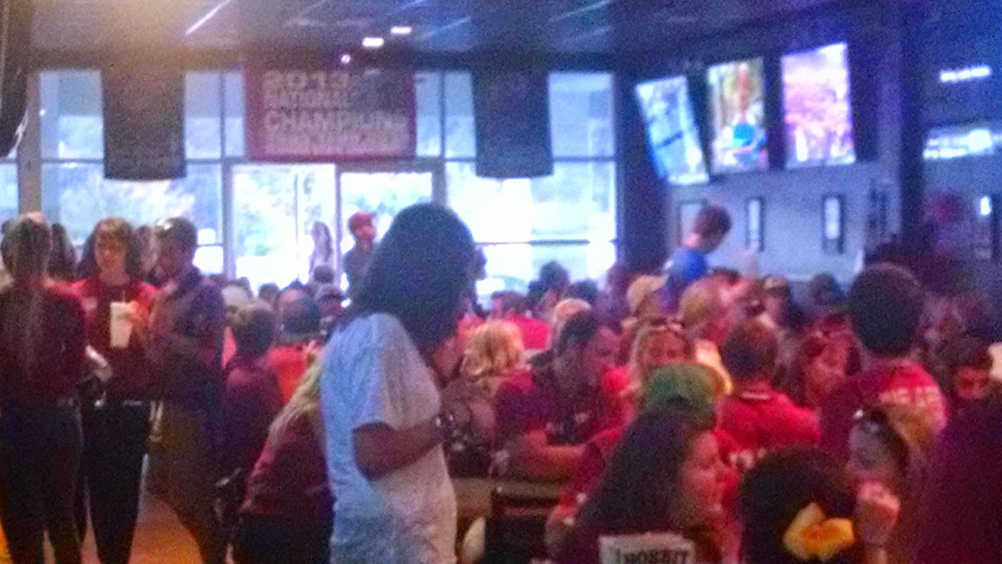 A full dining room on game day, tables packed and televisions on across the back wall.
