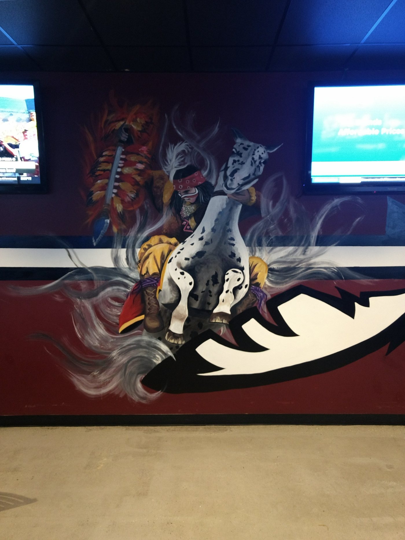 A hand-painted mural of a rider carrying a flaming spear on an Appaloosa horse, above a garnet and white spearhead.