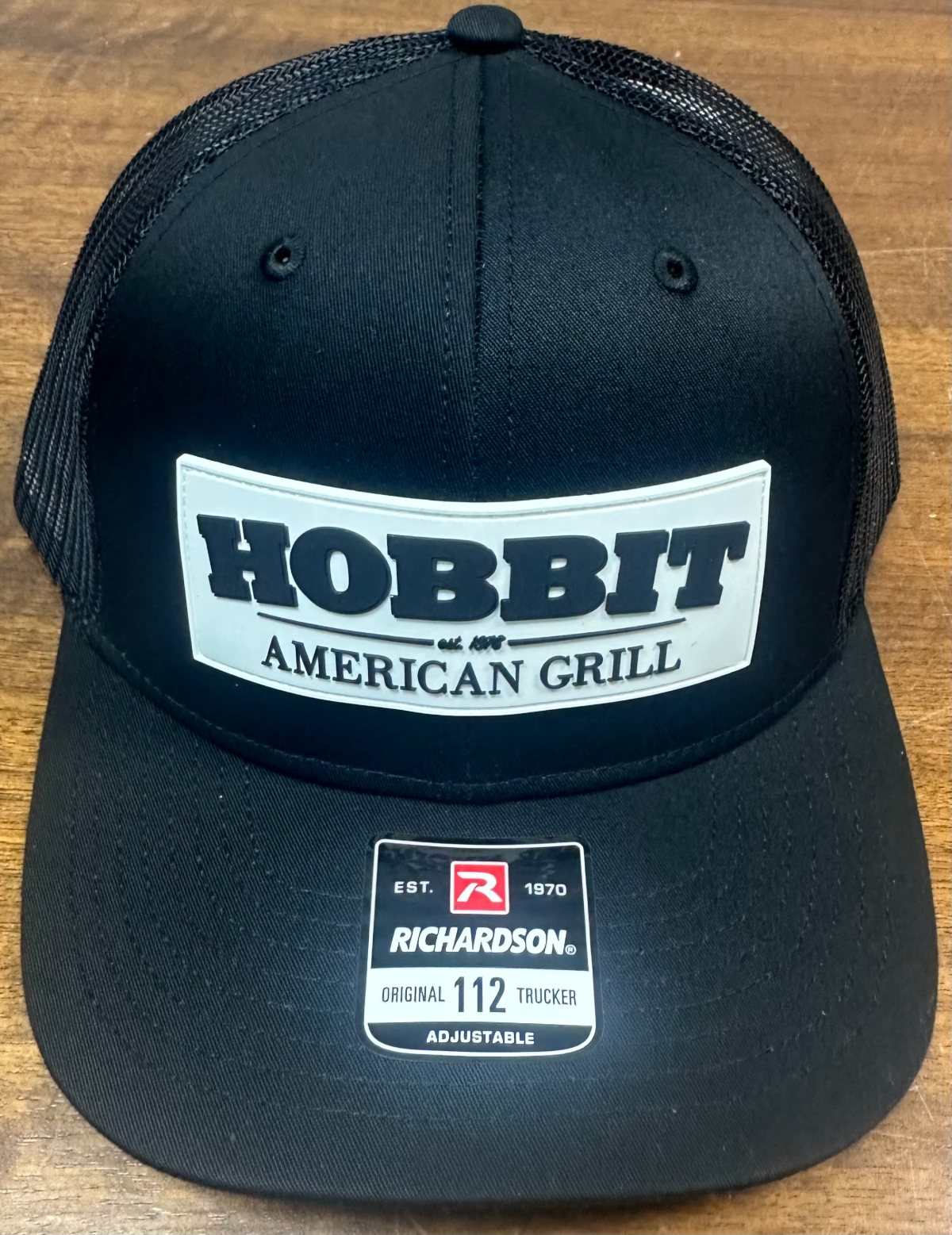 A black and brown mesh-back cap with a white Hobbit American Grill patch on the front.