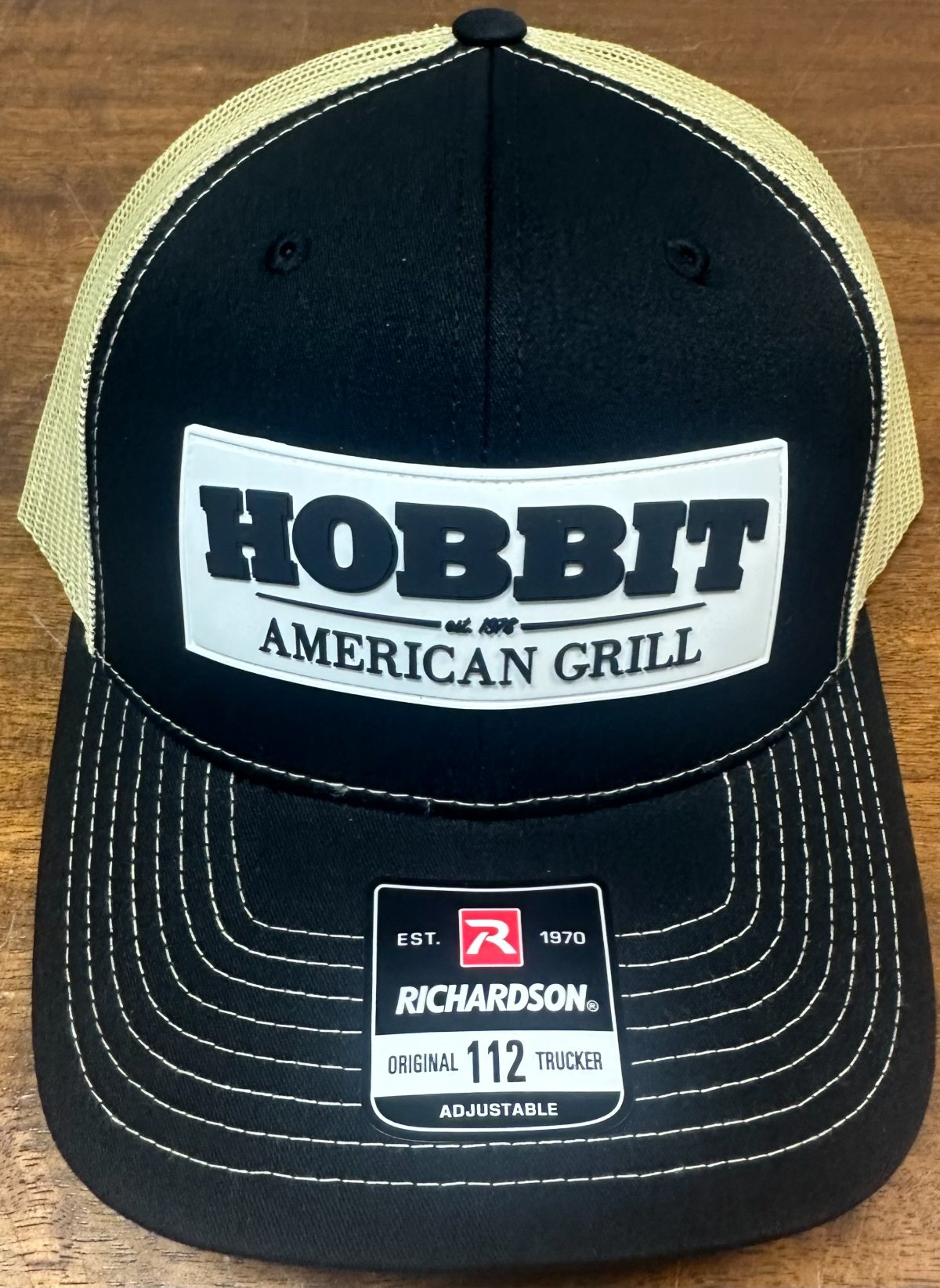 A black and cream mesh-back cap with a white Hobbit American Grill patch on the front.