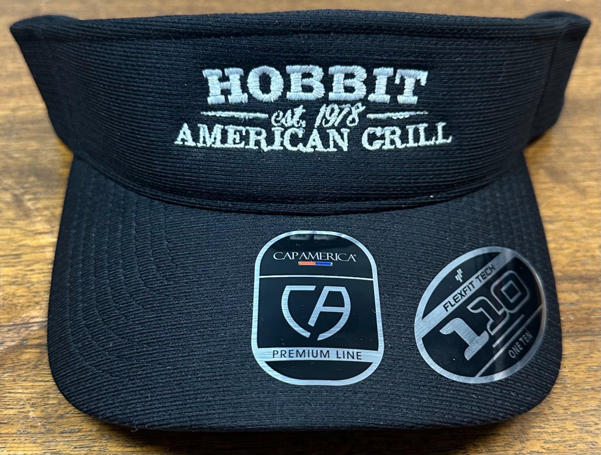 A black visor embroidered Hobbit American Grill in cream thread.